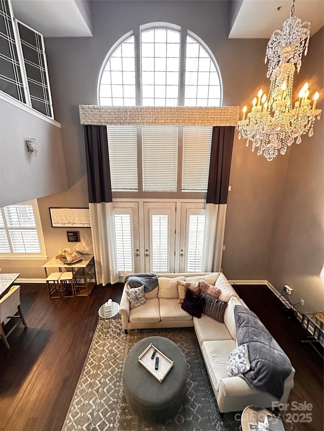 living area with a notable chandelier, baseboards, a high ceiling, and dark wood-type flooring