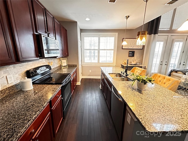 kitchen featuring hanging light fixtures, appliances with stainless steel finishes, decorative backsplash, light stone countertops, and a sink