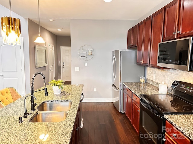 kitchen with pendant lighting, reddish brown cabinets, stainless steel appliances, a sink, and light stone counters