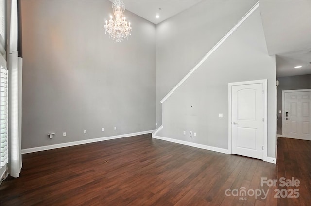 128 Steinbeck Way Unit E, Mooresville, NC 28117 - unfurnished living room with baseboards, a towering ceiling, a chandelier, and dark wood-type flooring