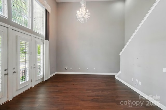 128 Steinbeck Way Unit E, Mooresville, NC 28117 - unfurnished dining area featuring a towering ceiling, baseboards, an inviting chandelier, and dark wood-type flooring