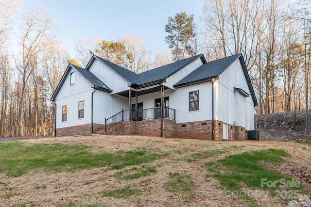 view of front facade featuring crawl space, roof with shingles, and central AC unit