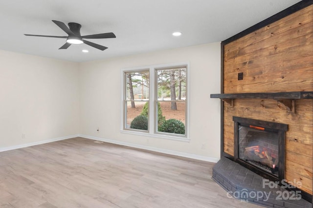 unfurnished living room with ceiling fan, light wood-type flooring, and a fireplace