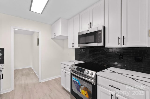 kitchen with light stone counters, stainless steel appliances, and white cabinets