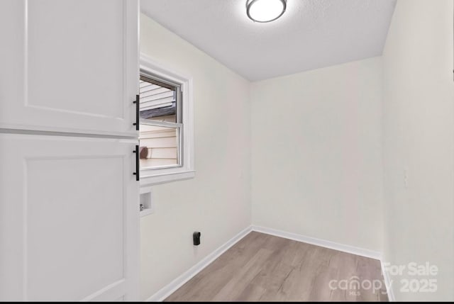 clothes washing area with hookup for a washing machine, a textured ceiling, and light wood-type flooring