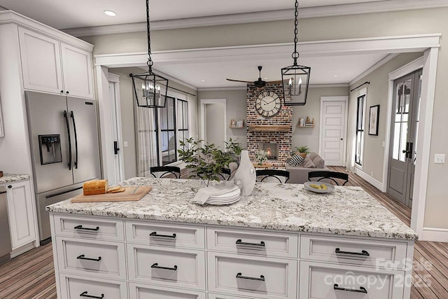 kitchen featuring a fireplace, white cabinets, open floor plan, ornamental molding, and stainless steel refrigerator with ice dispenser