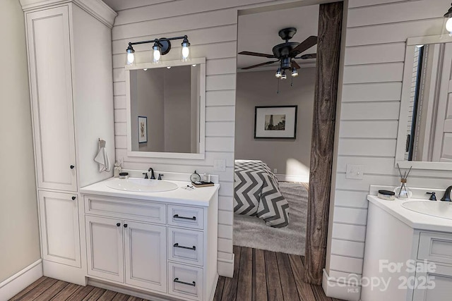 bathroom featuring wood finished floors, two vanities, and a sink