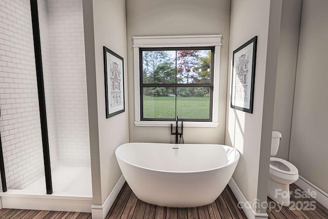 bathroom with a freestanding bath, wood finished floors, toilet, and baseboards