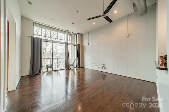 empty room featuring dark wood-type flooring, floor to ceiling windows, and ceiling fan