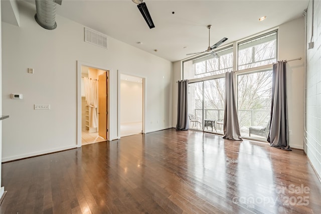 empty room featuring ceiling fan, hardwood / wood-style floors, and a wall of windows