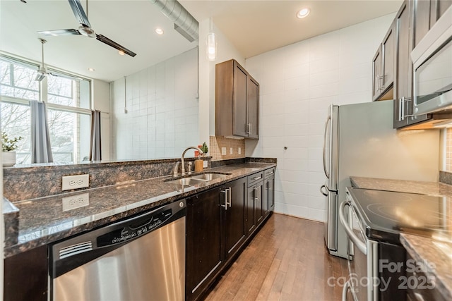 kitchen with sink, dark brown cabinets, stainless steel appliances, and dark stone counters