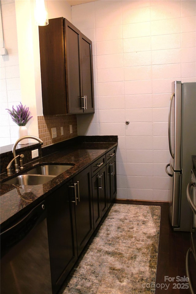 kitchen with sink, tile walls, dark stone counters, dark brown cabinetry, and stainless steel appliances