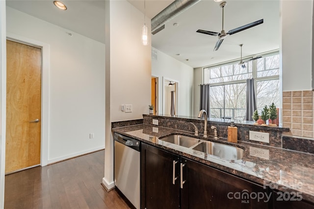 kitchen featuring dishwasher, sink, dark stone countertops, dark hardwood / wood-style flooring, and dark brown cabinetry