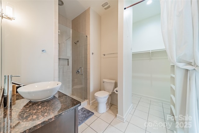 bathroom featuring tile patterned flooring, vanity, a shower with door, and toilet