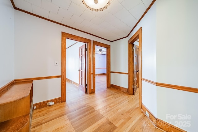 hall with ornamental molding and light hardwood / wood-style floors