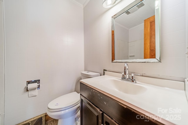 bathroom featuring tile walls, vanity, crown molding, and toilet