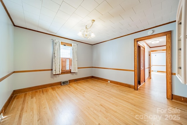 empty room with ornamental molding, a notable chandelier, and light wood-type flooring