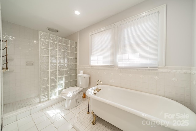 bathroom with tile patterned floors, toilet, independent shower and bath, and tile walls