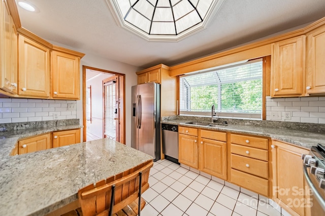 kitchen with sink, appliances with stainless steel finishes, backsplash, light stone counters, and light tile patterned flooring