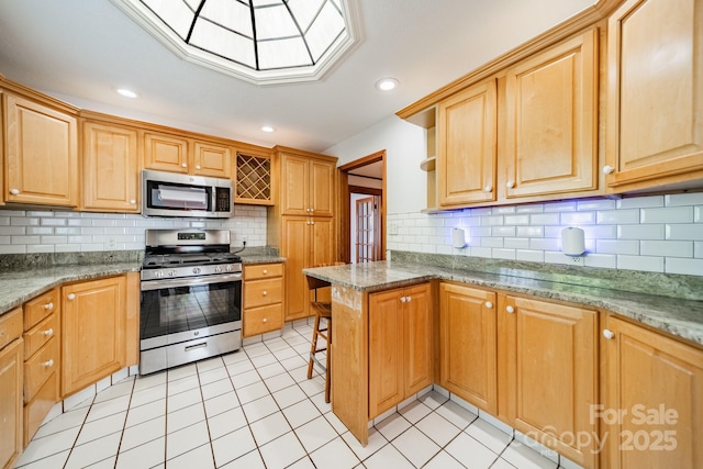 kitchen with appliances with stainless steel finishes, light tile patterned floors, backsplash, and kitchen peninsula