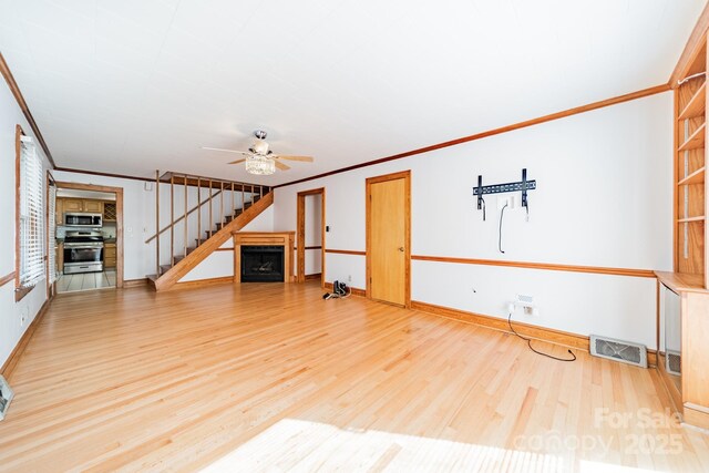 531 Elm St, Salisbury, NC 28144 - unfurnished living room featuring wood finished floors, ornamental molding, a ceiling fan, stairs, and baseboards
