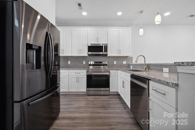 kitchen with pendant lighting, sink, stainless steel appliances, light stone countertops, and white cabinets