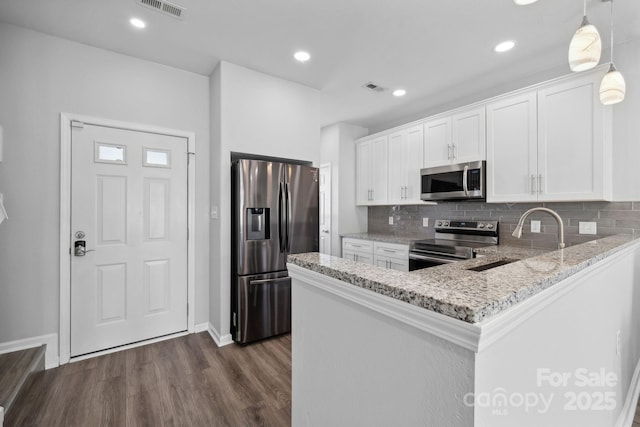 kitchen with sink, white cabinetry, hanging light fixtures, appliances with stainless steel finishes, and kitchen peninsula