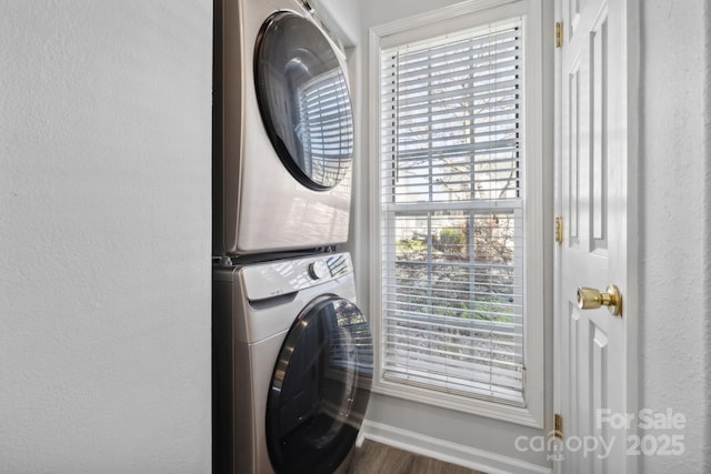 laundry area featuring stacked washer / drying machine and wood-type flooring