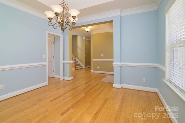 spare room featuring crown molding, an inviting chandelier, and light wood-type flooring