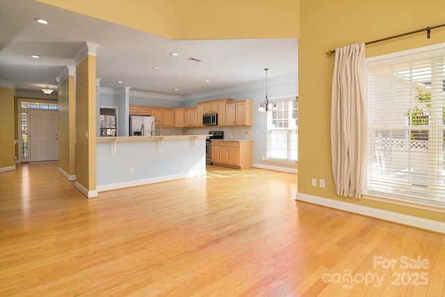 unfurnished living room featuring an inviting chandelier, ornamental molding, and light wood-type flooring