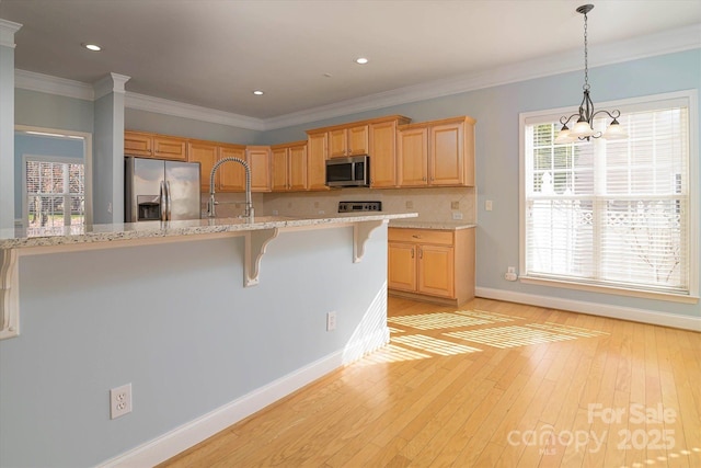 kitchen with appliances with stainless steel finishes, light wood-type flooring, a wealth of natural light, and a kitchen breakfast bar