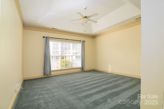 spare room with dark carpet, a tray ceiling, and crown molding