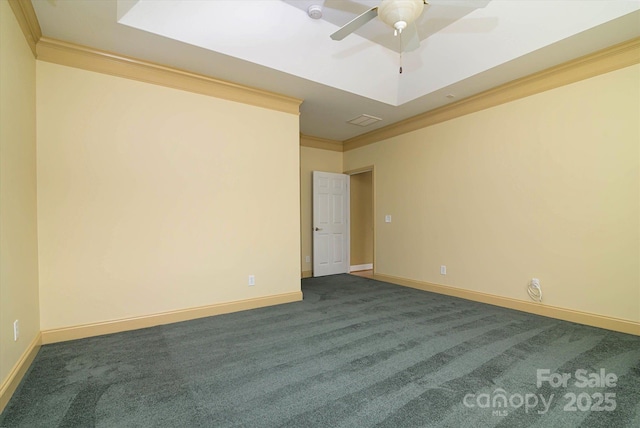 spare room with dark colored carpet, crown molding, and ceiling fan