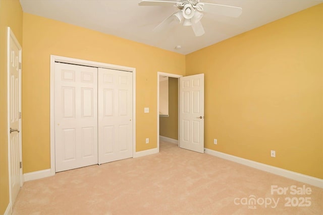 unfurnished bedroom with ceiling fan, light colored carpet, and a closet