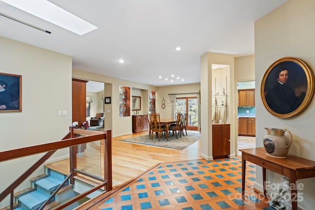 hall featuring a skylight and light hardwood / wood-style floors