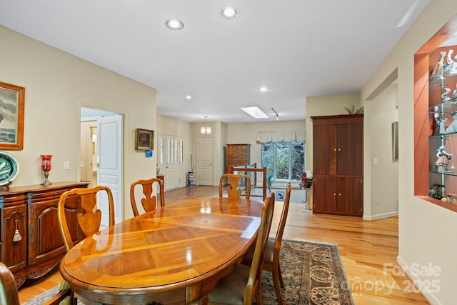 dining room featuring a skylight and light wood-type flooring