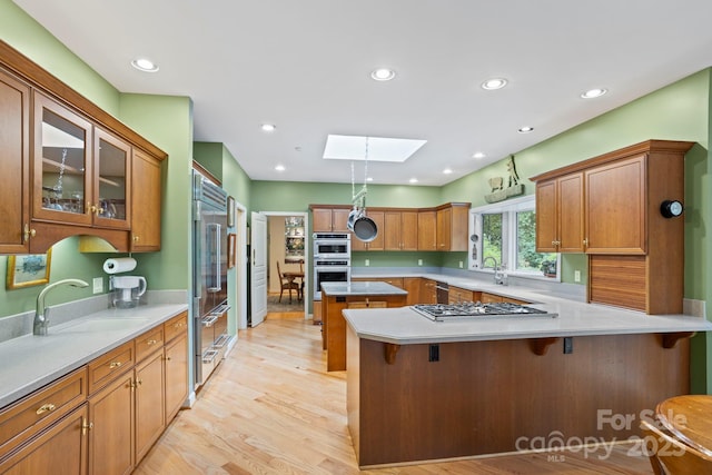 kitchen with sink, a breakfast bar area, appliances with stainless steel finishes, a skylight, and a center island