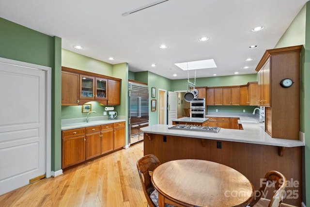 kitchen featuring appliances with stainless steel finishes, a skylight, sink, a kitchen breakfast bar, and kitchen peninsula