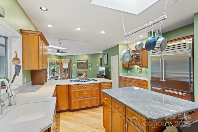 kitchen featuring sink, appliances with stainless steel finishes, a skylight, a center island, and kitchen peninsula