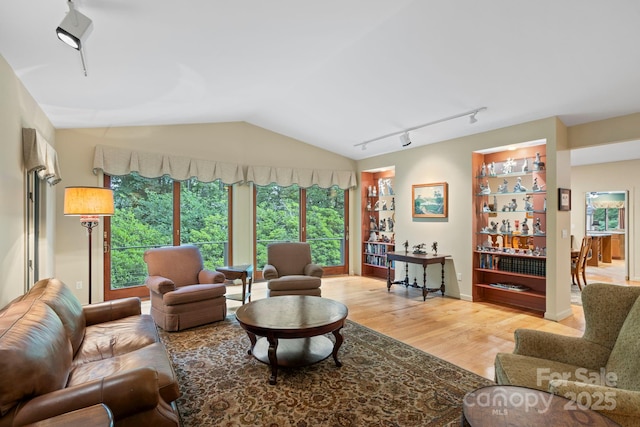 living room featuring hardwood / wood-style flooring, vaulted ceiling, and rail lighting