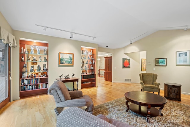 living room with lofted ceiling, light hardwood / wood-style flooring, and track lighting