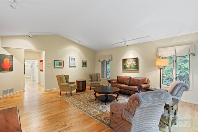 living room featuring vaulted ceiling, track lighting, and light hardwood / wood-style floors