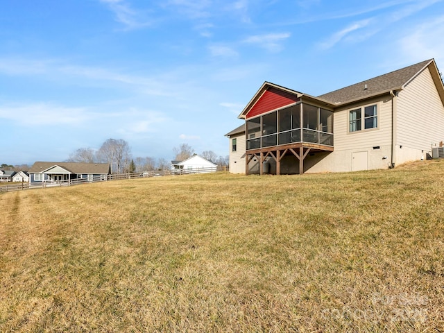 rear view of property with a sunroom, cooling unit, and a lawn