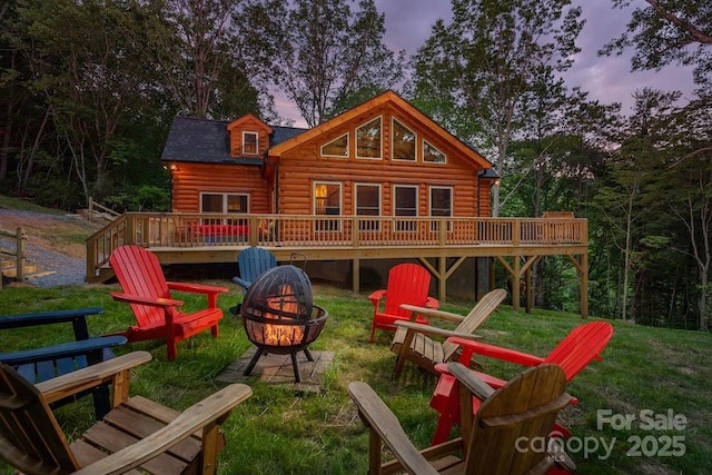 playground at dusk featuring a yard, a deck, and a fire pit