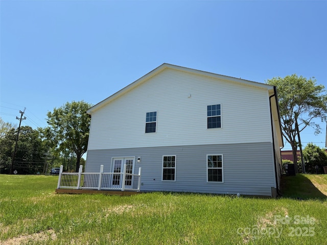 rear view of house featuring a deck, french doors, and a lawn