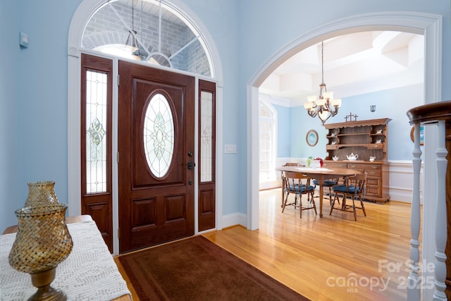 foyer entrance featuring an inviting chandelier, hardwood / wood-style floors, and plenty of natural light