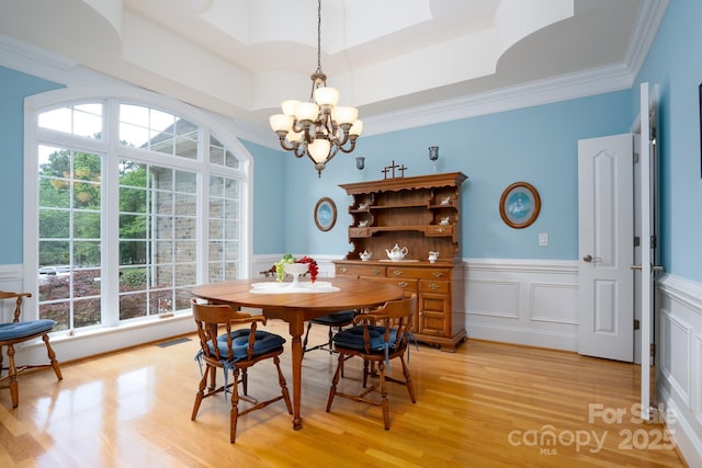 dining room featuring ornamental molding, light wood-type flooring, and a tray ceiling