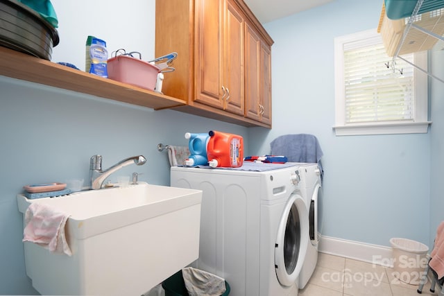 washroom with cabinets, sink, washing machine and dryer, and light tile patterned floors