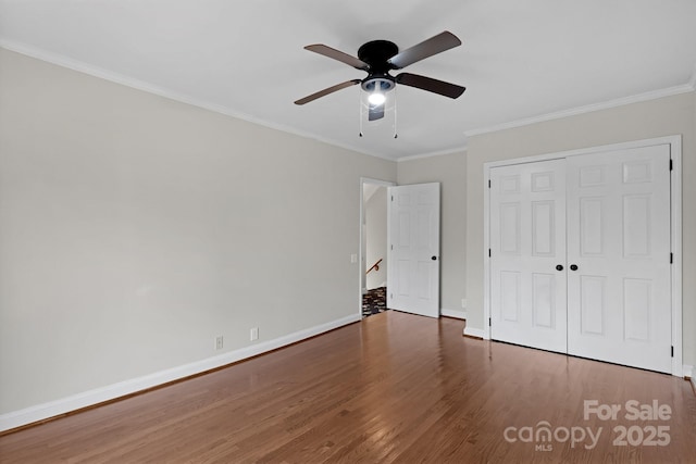 unfurnished bedroom featuring crown molding, dark wood-type flooring, ceiling fan, and a closet