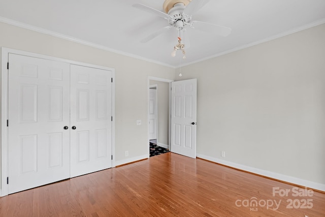 unfurnished bedroom with crown molding, ceiling fan, hardwood / wood-style floors, and a closet